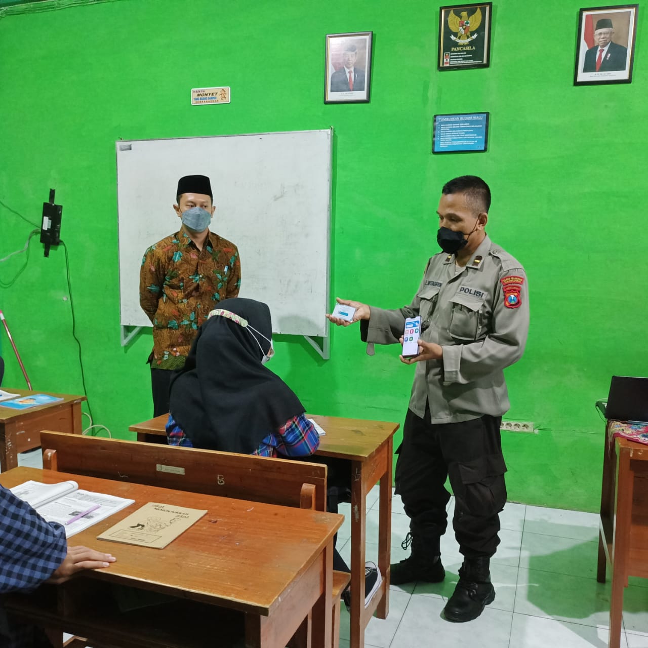 PERSONIL POLSEK KREMBANGAN BERI HIMBAUAN PROTOKOL KESEHATAN DAN SOSIALISASIKAN APLIKASI PEDULI LINDUNGI  DI SEKOLAH